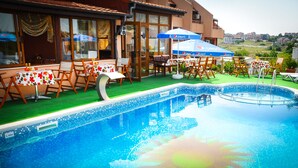 Zona de piscina con mobiliario para comer, mesas y sillas, y vistas del paisaje circundante.