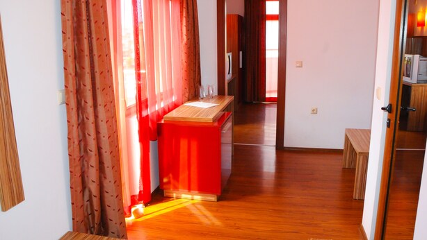 Un pasillo con suelo de madera, un armario rojo y un banco de madera.