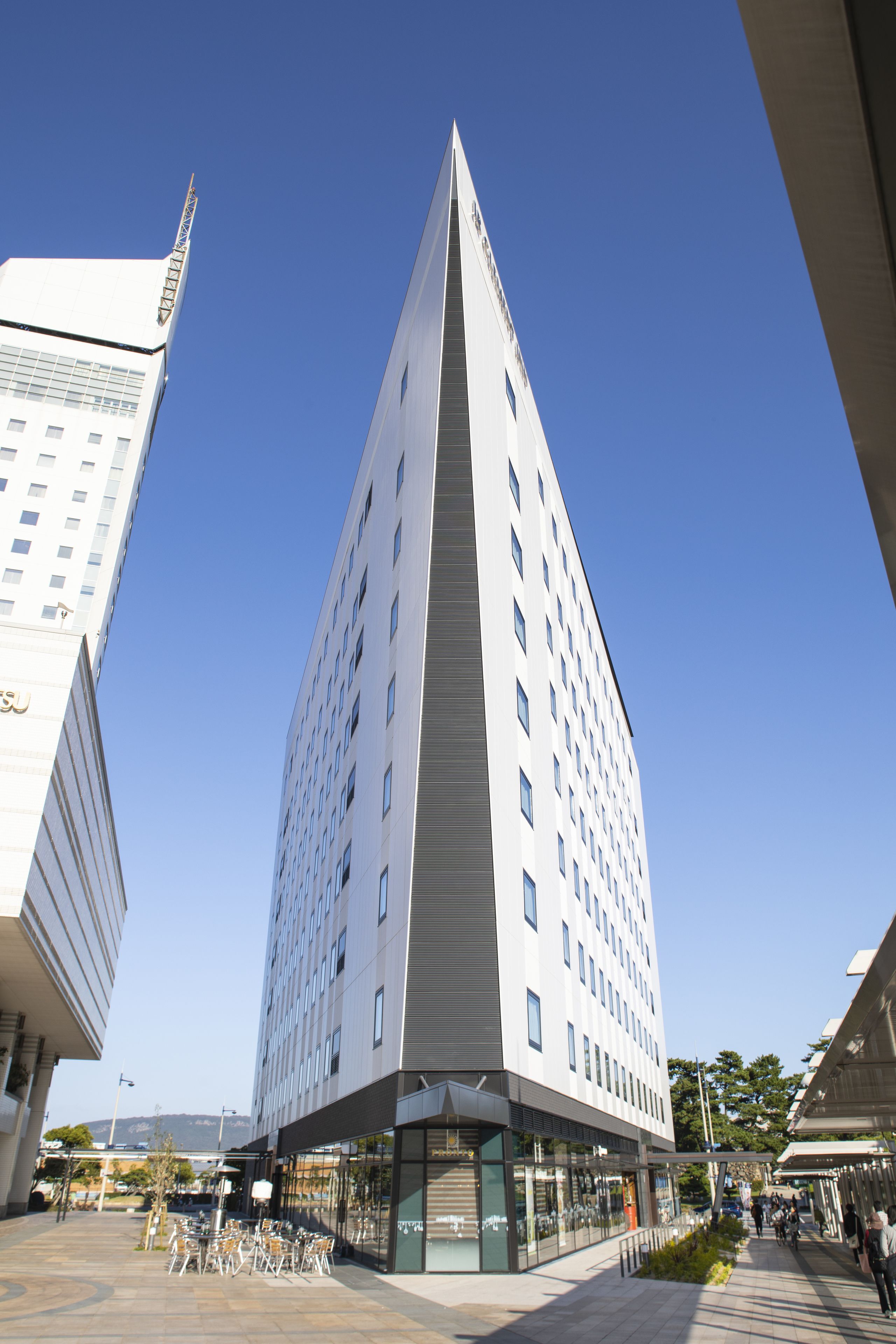 Een modern hoog hotel met een opvallend driehoekig ontwerp, meerdere verdiepingen en een glazen gevel.