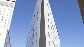 Een modern hoog hotel met een opvallend driehoekig ontwerp, meerdere verdiepingen en een glazen gevel.