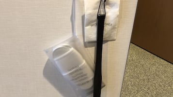 Una bolsa de plástico transparente con una correa negra, una bolsa de papel blanca con el texto "SHOEPRISHER" y un objeto blanco sobre una superficie texturizada.