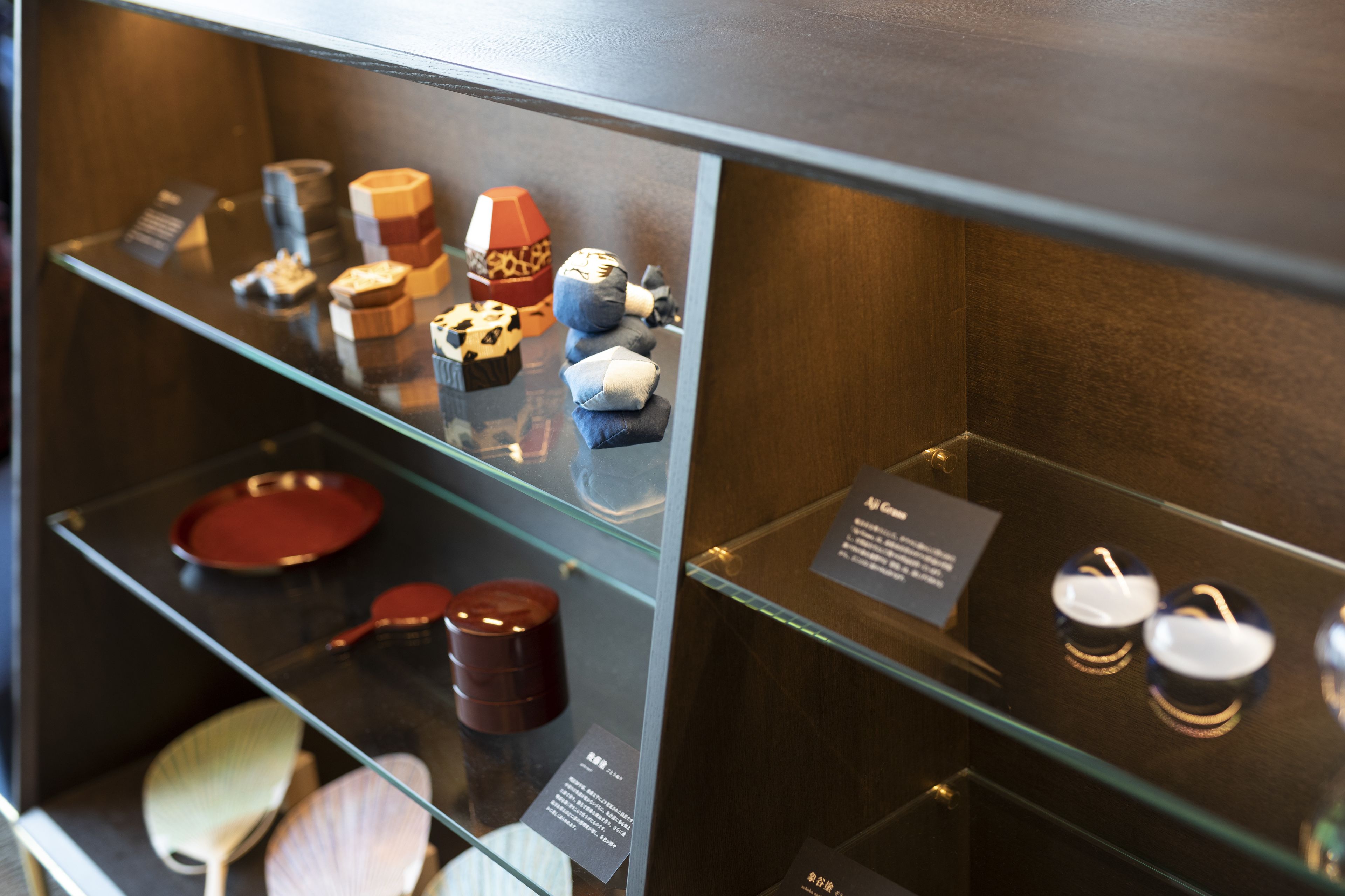 A display case with various items including a red plate, a wooden spoon, and a small brown container.