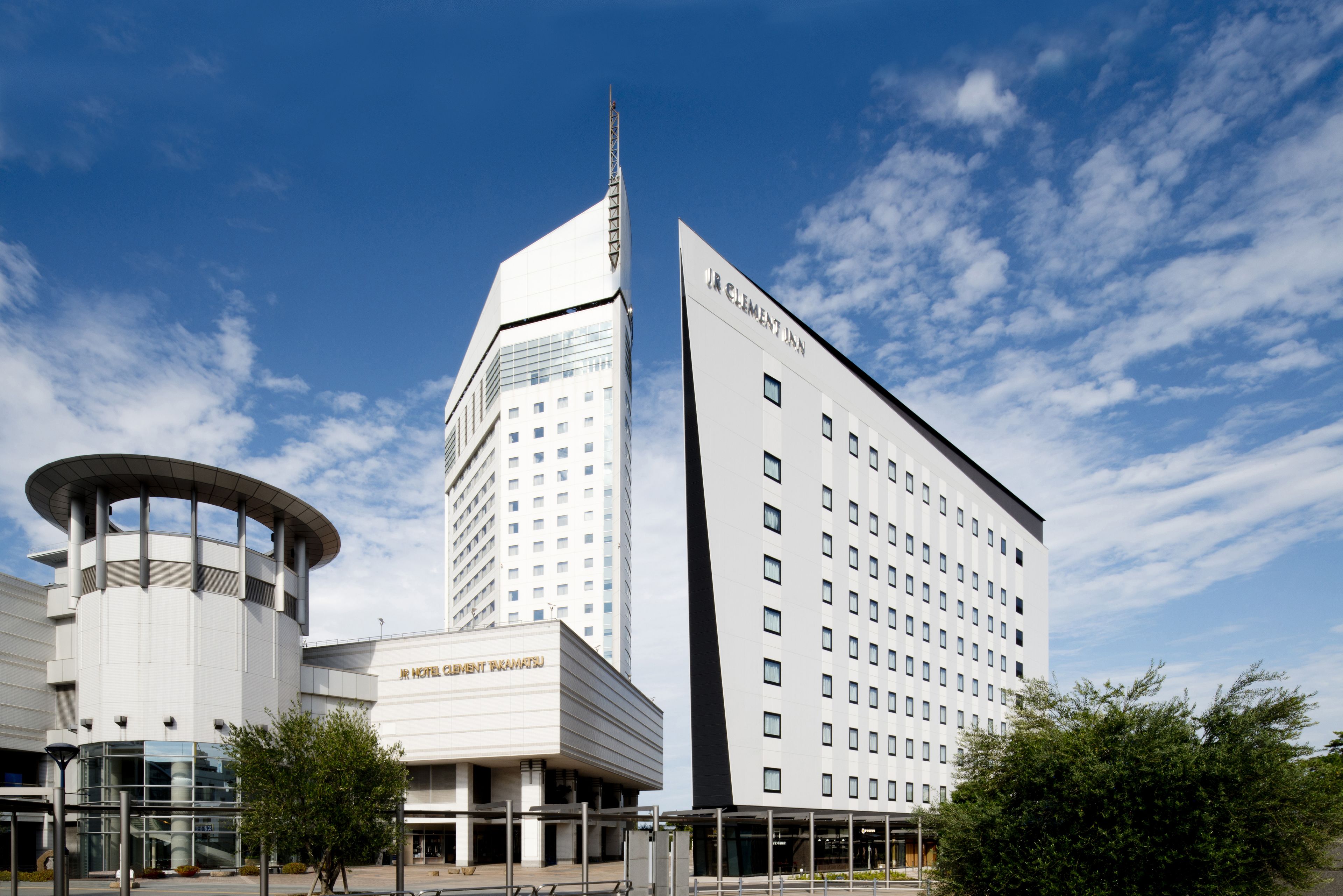 Een modern hotel met een cilindrische toren, een hoog rechthoekig gebouw en een plat dak.