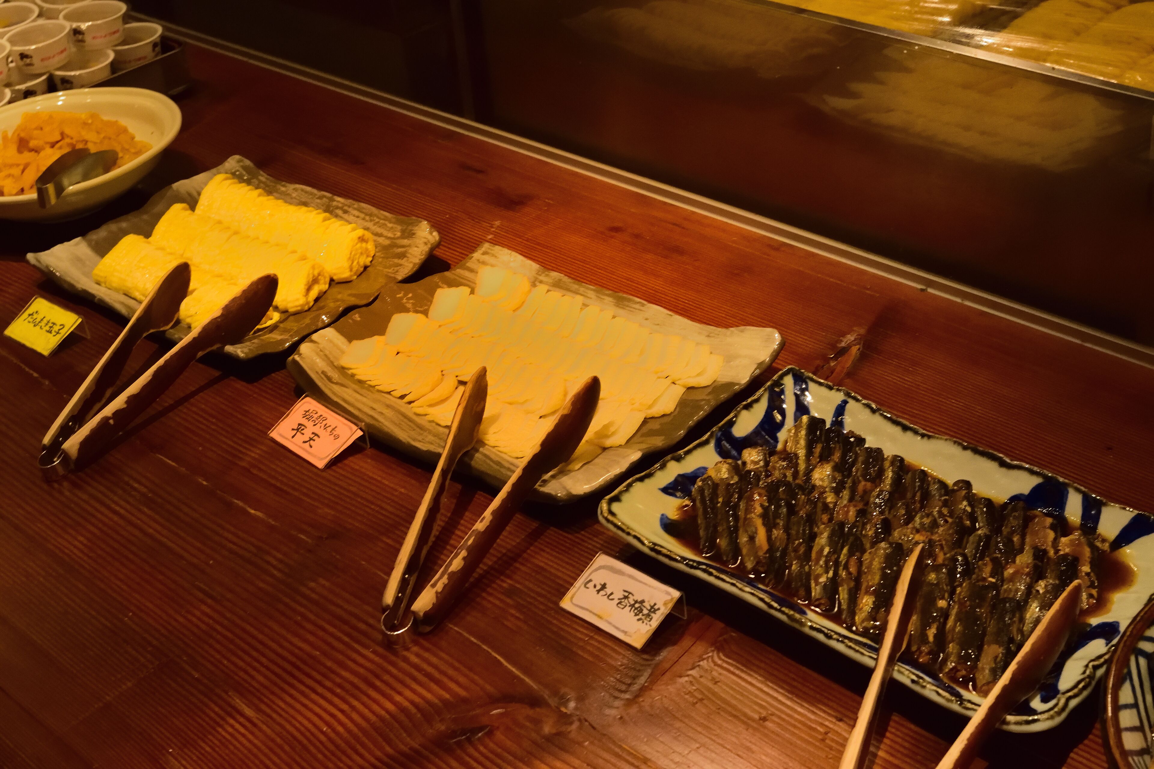 Een buffet met diverse gerechten, waaronder een schaal rijst, een bord vis en een portie ingemaakte groenten.