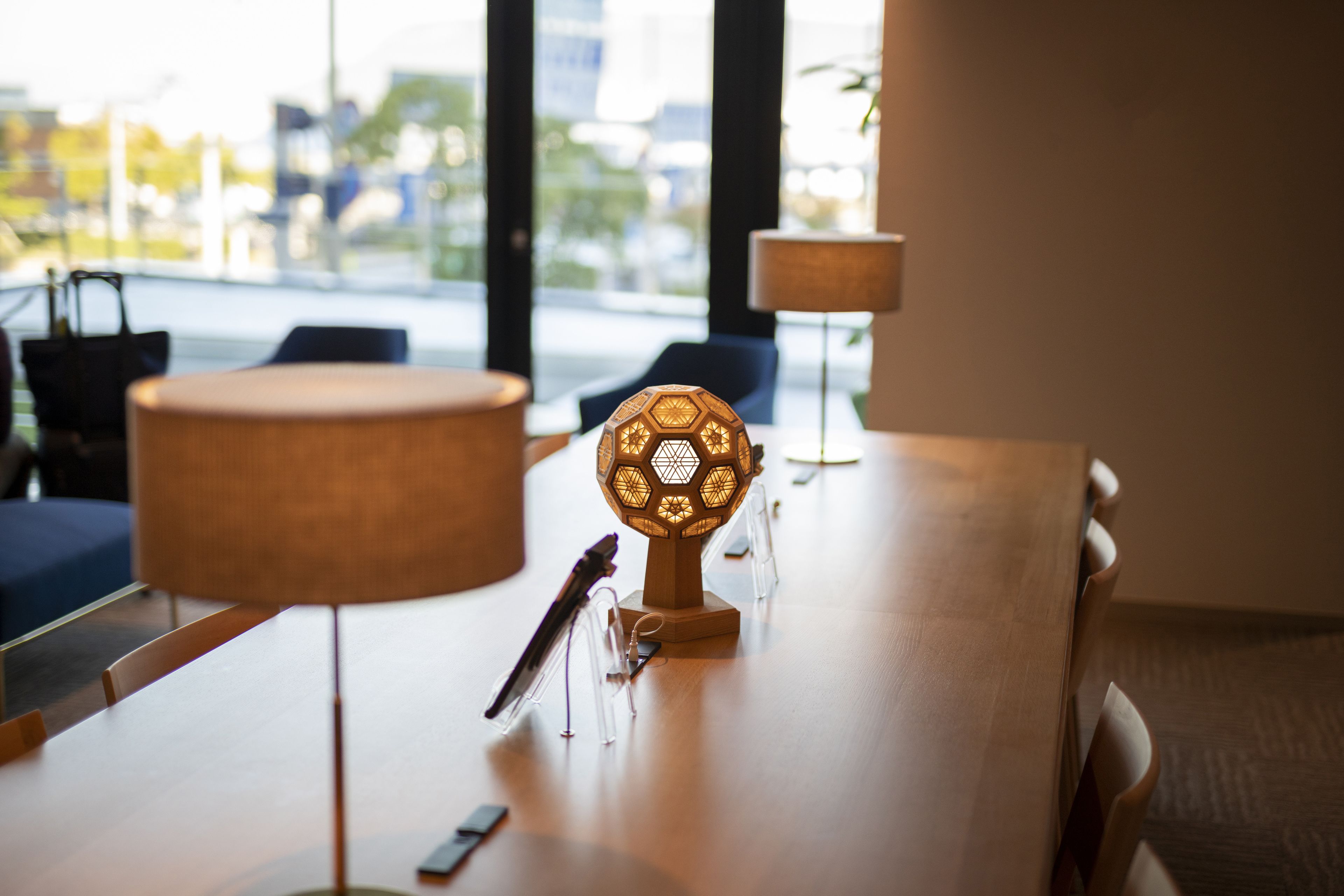 Une table de conférence avec une lampe, un porte-stylos et un smartphone.