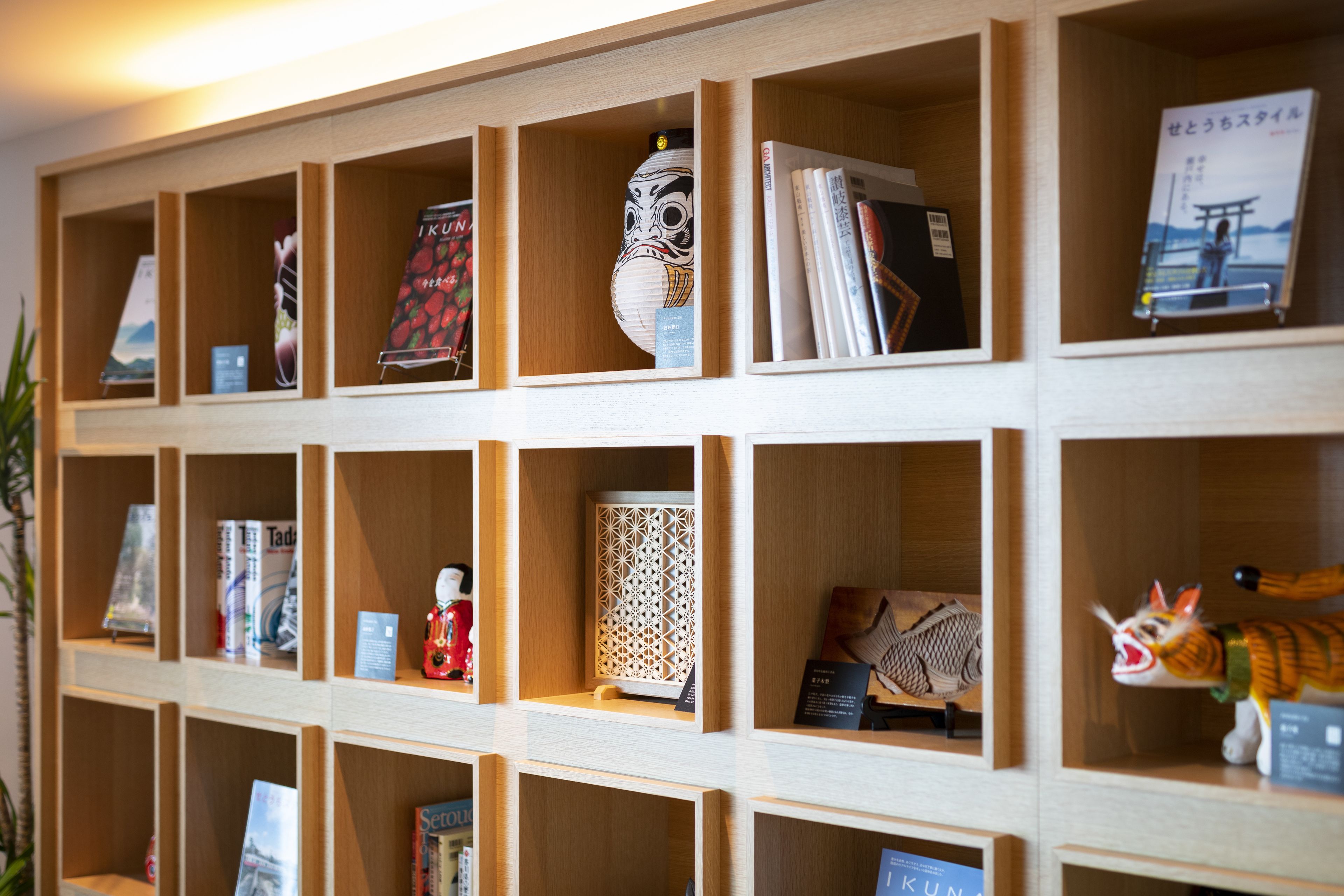 A wall with multiple wooden shelves displaying various items including books, a decorative mask, and a small figurine.