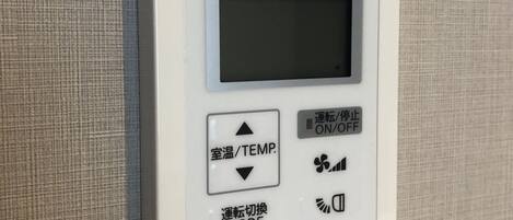 Un termostato Mitsubishi eléctrico con botones de ajuste de temperatura y selector de modo.