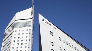 Un bâtiment moderne, facilement reconnaissable grâce à une grande enseigne « JR CLEMENT INN », caractérisé par une façade à motifs géométriques et un design épuré et anguleux.