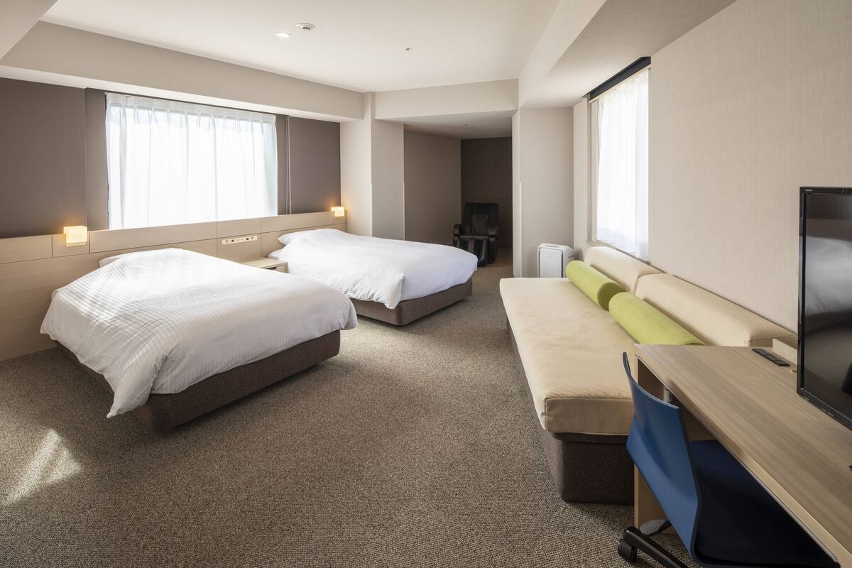Une chambre d’hôtel avec deux lits, un bureau, une télévision et une chaise.