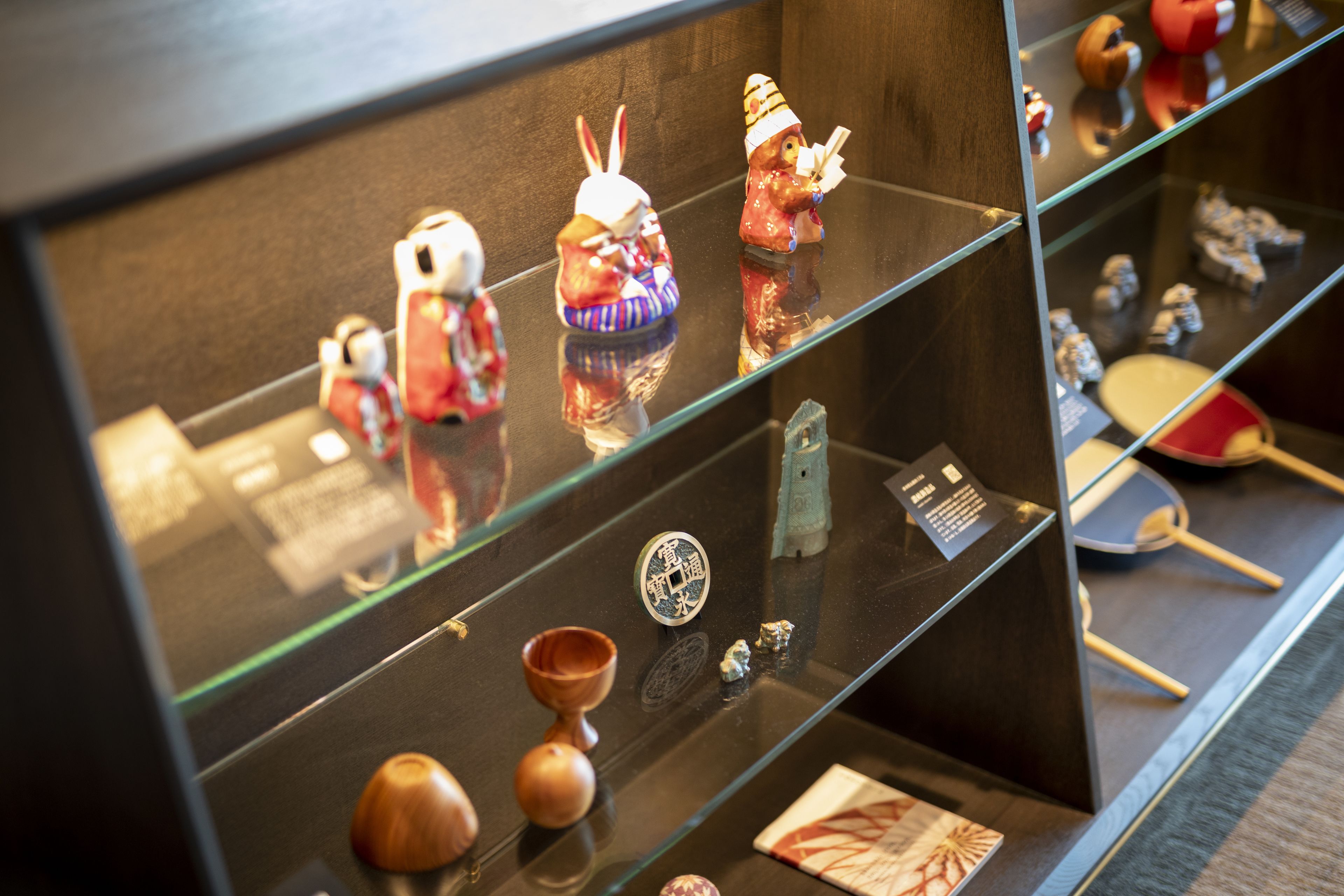 A display case with various small figurines and artifacts, including a red and white figure, a figure with a hat, and a small wooden object.