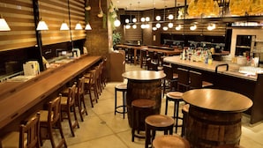 A bar area with wooden stools, a long counter, and hanging pendant lights. - JR Clement Inn Takamatsu (Takamatsu)