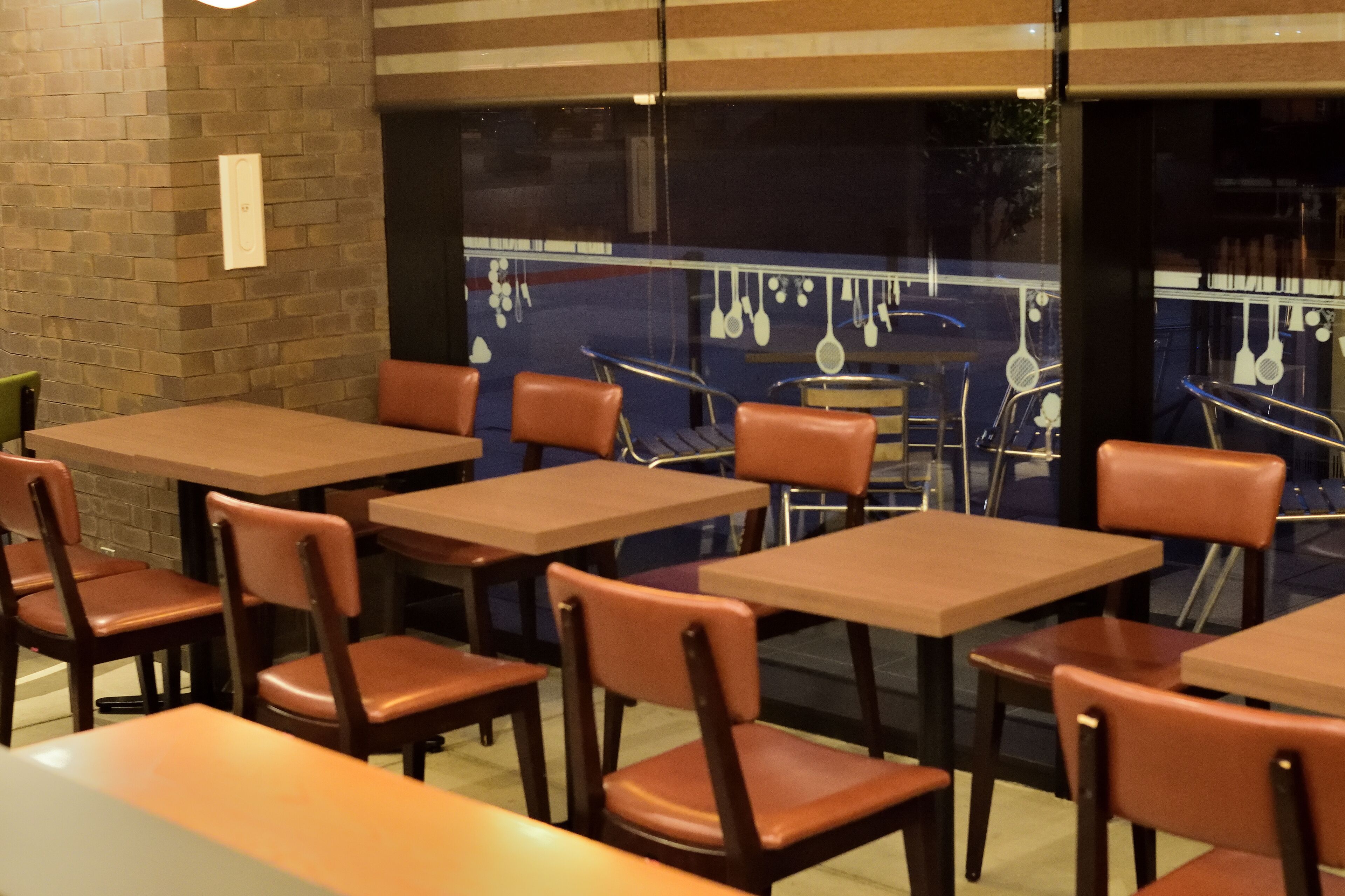 A restaurant interior with brick walls, wooden tables, and leather chairs.