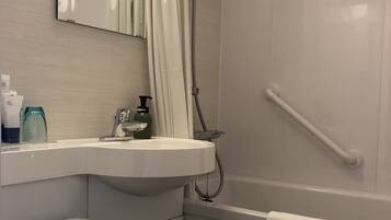Un baño moderno con inodoro blanco, lavamanos, ducha y barandilla.