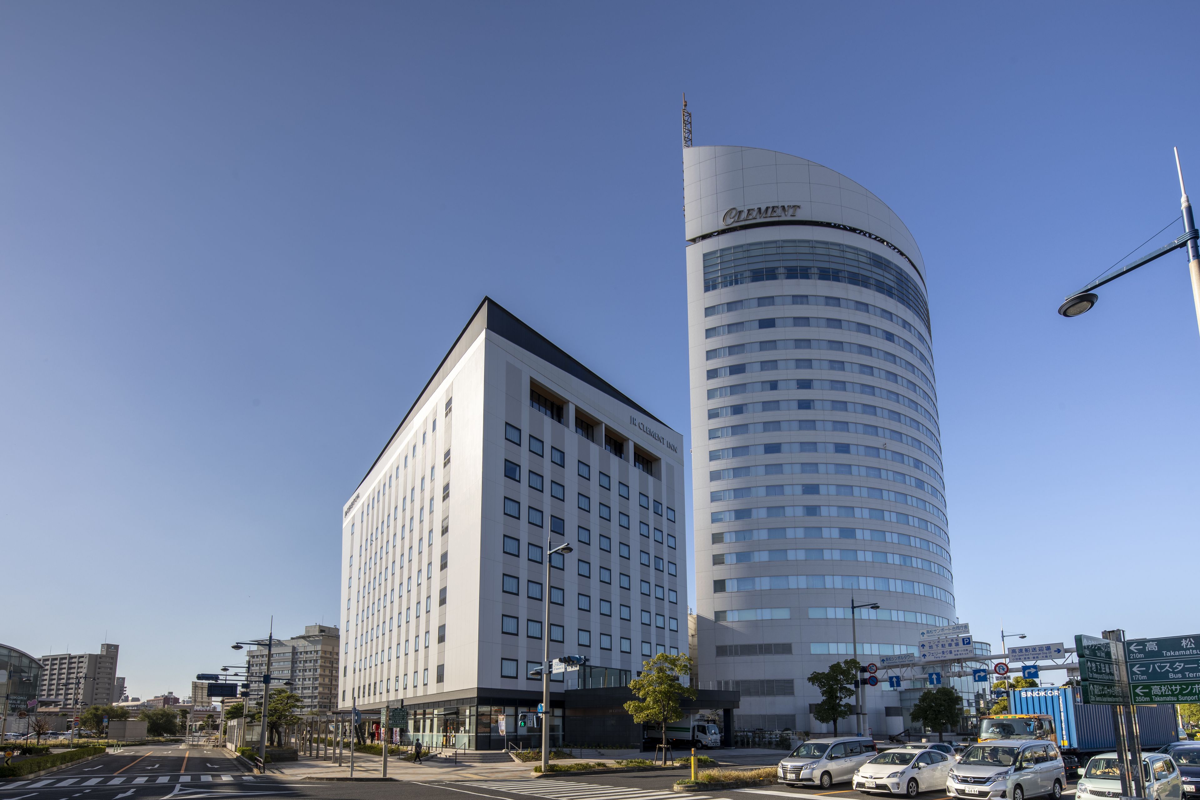 Un hotel moderno con fachada curva y un edificio de techo plano contiguo.