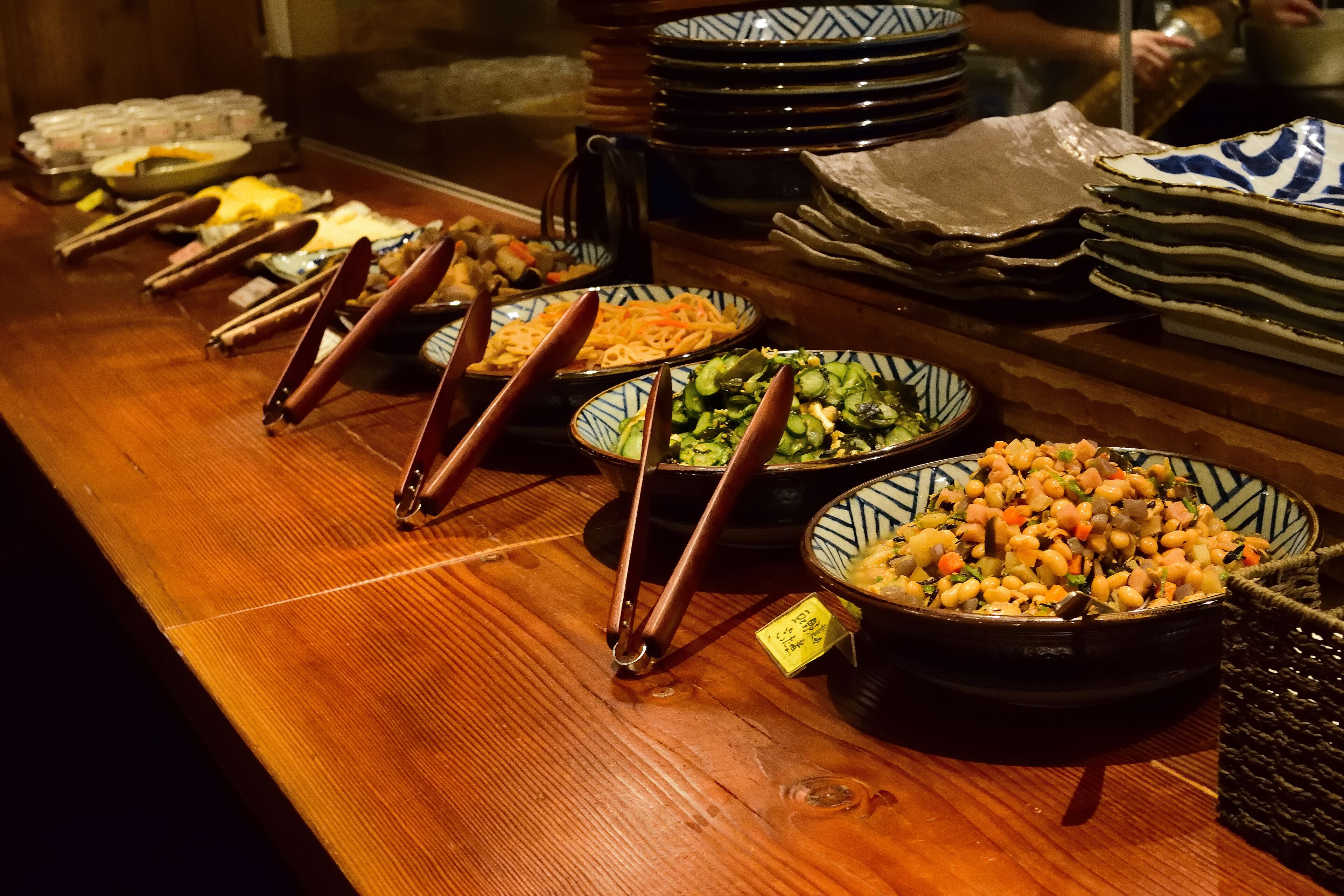 A buffet table with various dishes and utensils.