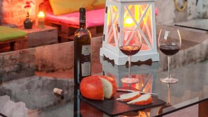 Una mesa de vidrio con una botella de vino, un farolillo y una hogaza de pan.