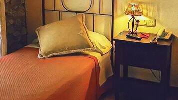 Habitación de hotel con dos camas individuales, una mesita de noche con lámpara y teléfono.
