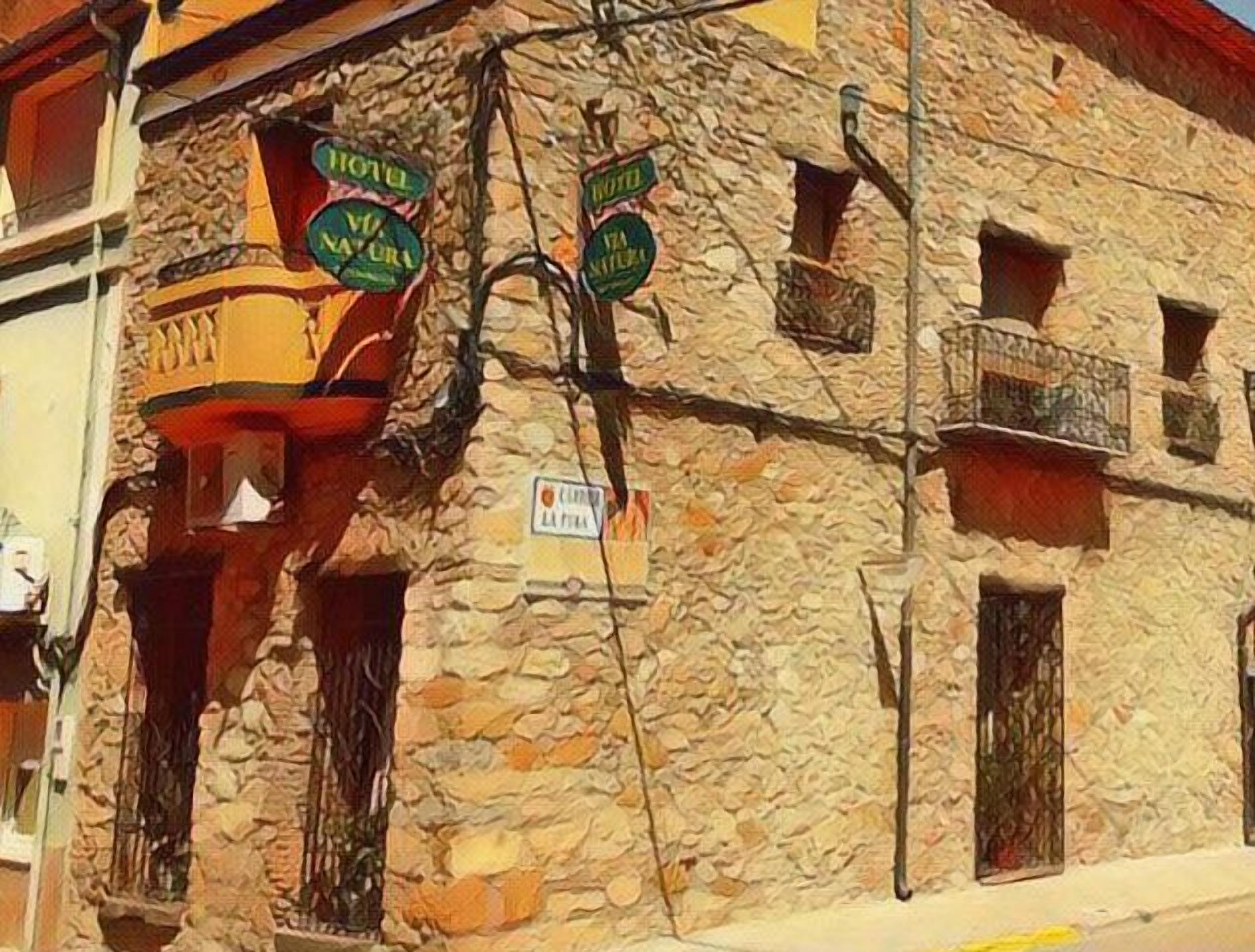 Un edificio de piedra con varios balcones y carteles que indican que es un hotel.