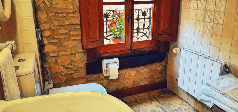 A bathroom with a bathtub, a toilet, and a window with decorative iron bars.