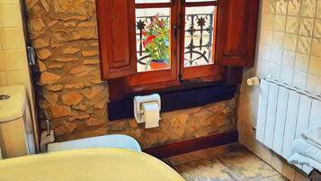 A bathroom with a bathtub, a toilet, and a window with decorative iron bars.