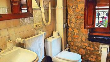 Une salle de bain avec une baignoire, des toilettes et une fenêtre donnant sur des plantes.