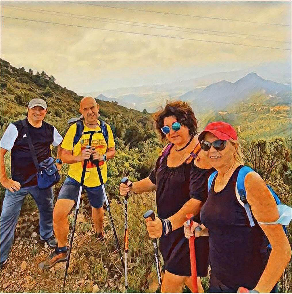 Un groupe de personnes fait de la randonnée en montagne, avec des sacs à dos et des bâtons de marche.
