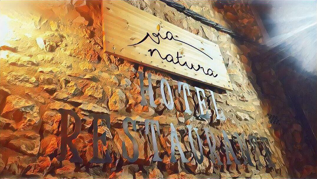Un muro de piedra rústica con un letrero de madera que dice "HOTEL RESTAURANT".