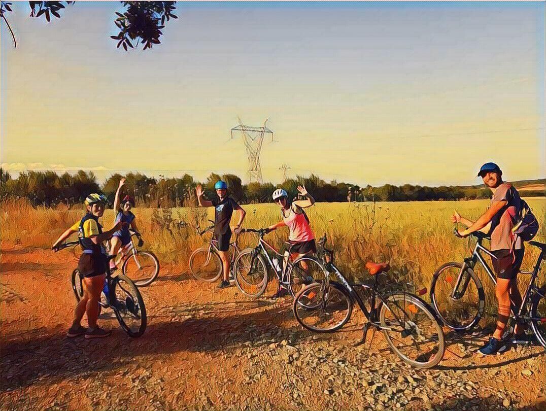 A group of cyclists in a rural setting with a dirt path and a power line in the background.