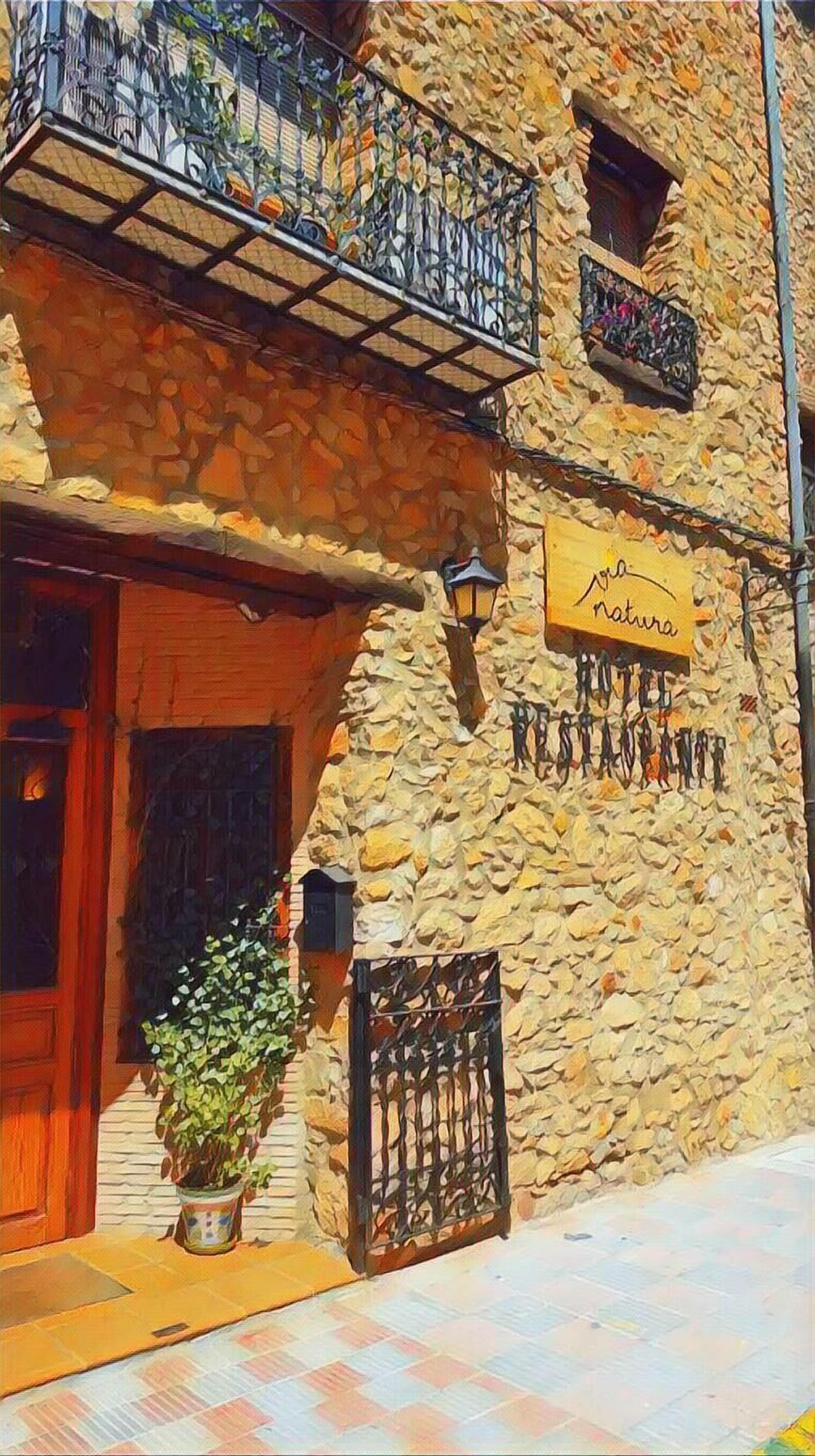 Un edificio de piedra con una puerta de madera, un balcón con barandilla de hierro forjado y un cartel que dice "natura".