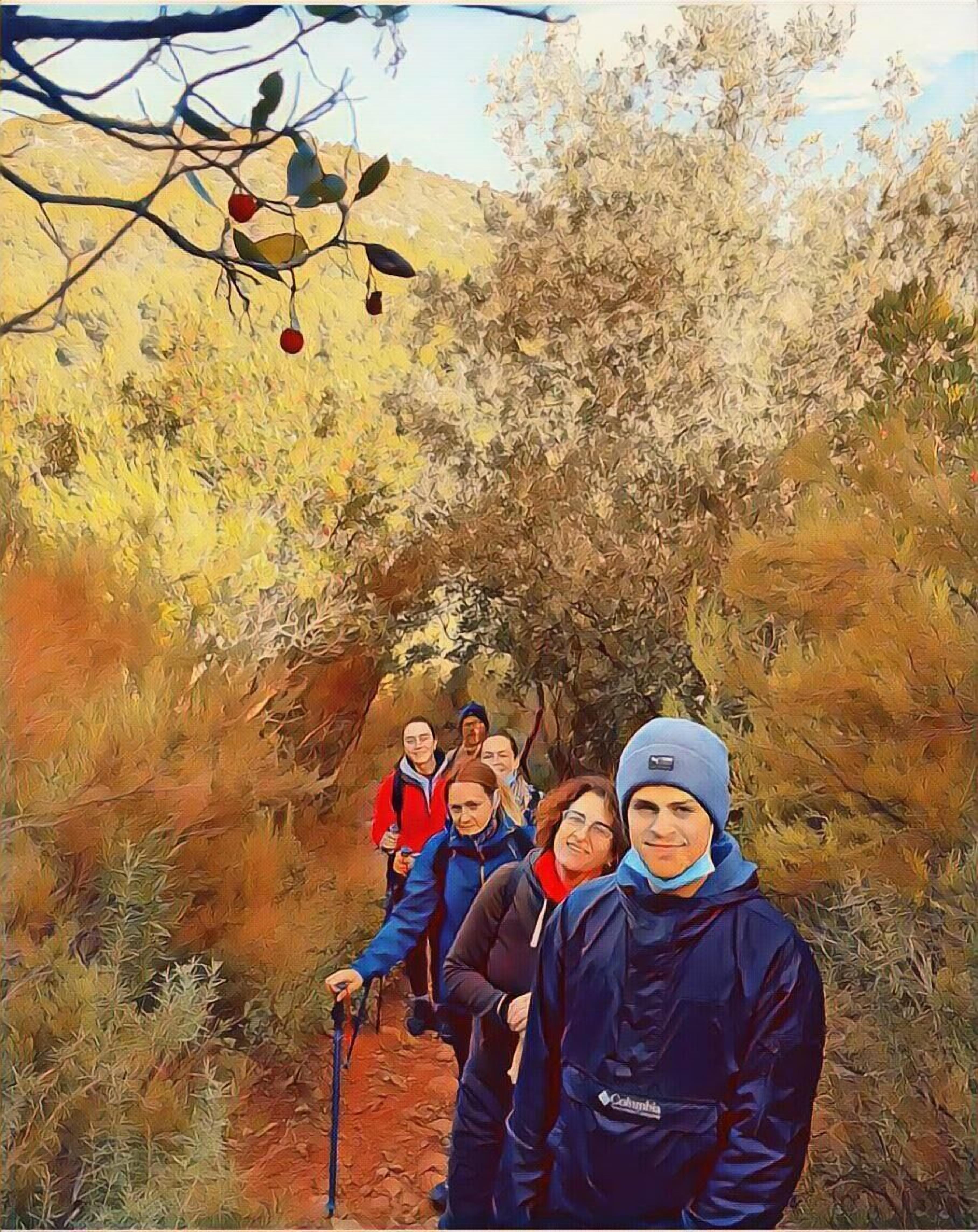 Eine Gruppe Wanderer auf einem Pfad, umgeben von trockener Vegetation und Bäumen.