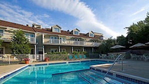 A swimming pool with clear blue water, surrounded by lounge chairs and umbrellas, with a building in the background. - Sag Harbor Inn (Sag Harbor)