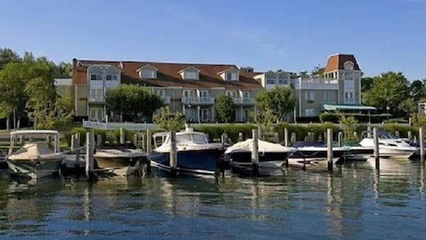 A waterfront property with a large house, multiple boats docked, and lush greenery. - Sag Harbor Inn (Sag Harbor)