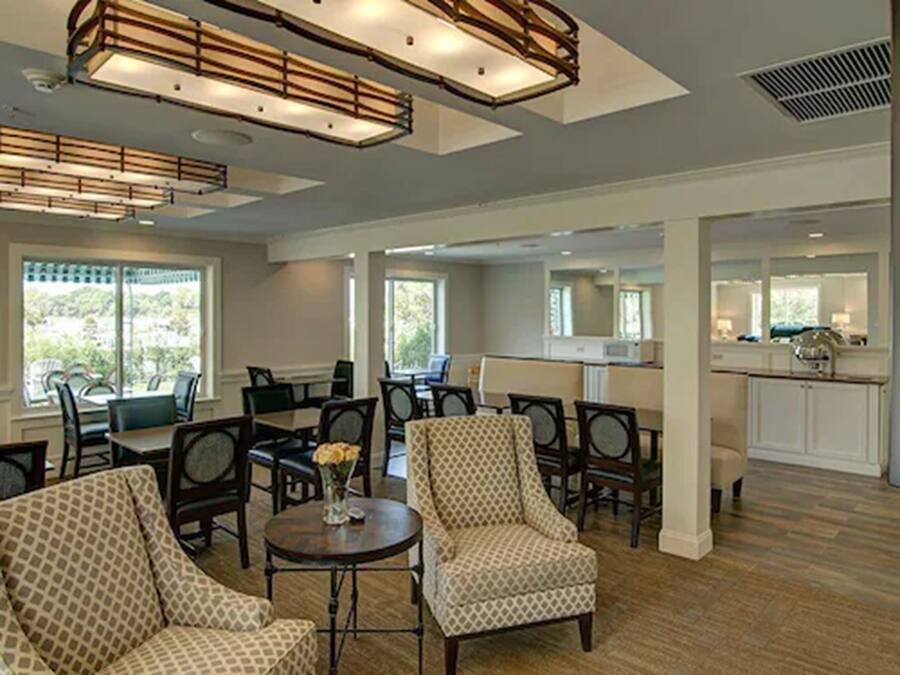 A spacious lobby with multiple seating areas, a kitchen area, and large windows providing natural light.