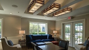 A hotel lobby with a sofa, chairs, tables, and a large window. - Sag Harbor Inn (Sag Harbor)