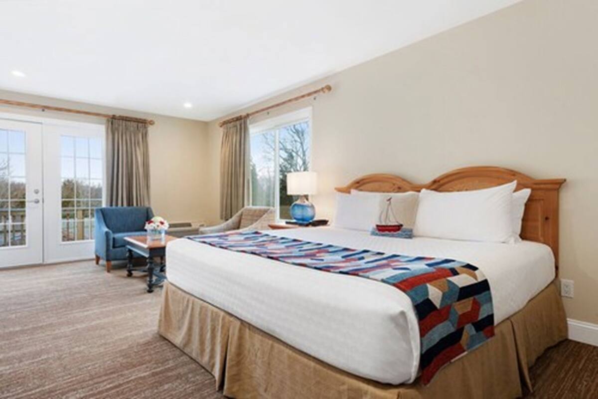 A hotel room with a large bed, a desk, a chair, and a window with curtains.
