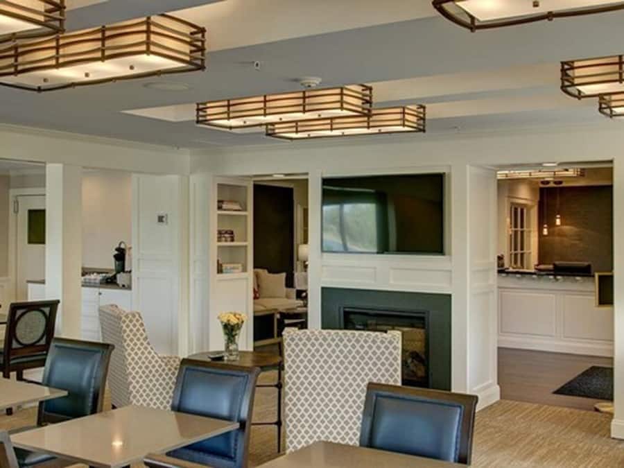 A modern interior with a dining area, a fireplace, and a kitchen visible through an open door.