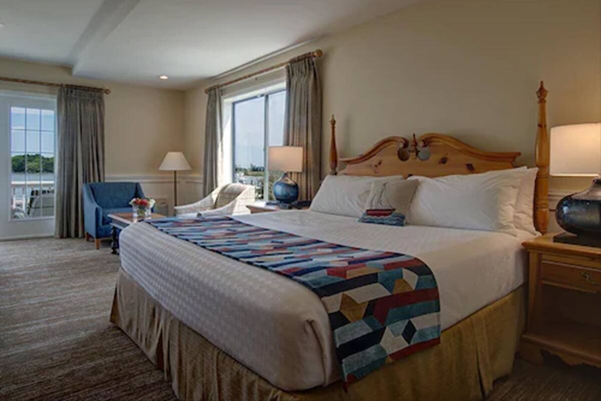 A hotel room with a large bed, a chair, a desk, and a view of the outdoors.