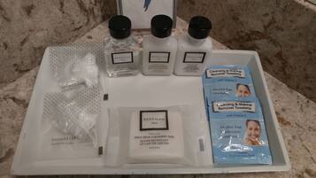 A tray with various grooming products including a shower cap, goat milk cleansing bar, and cleansing & makeup remover towelettes.