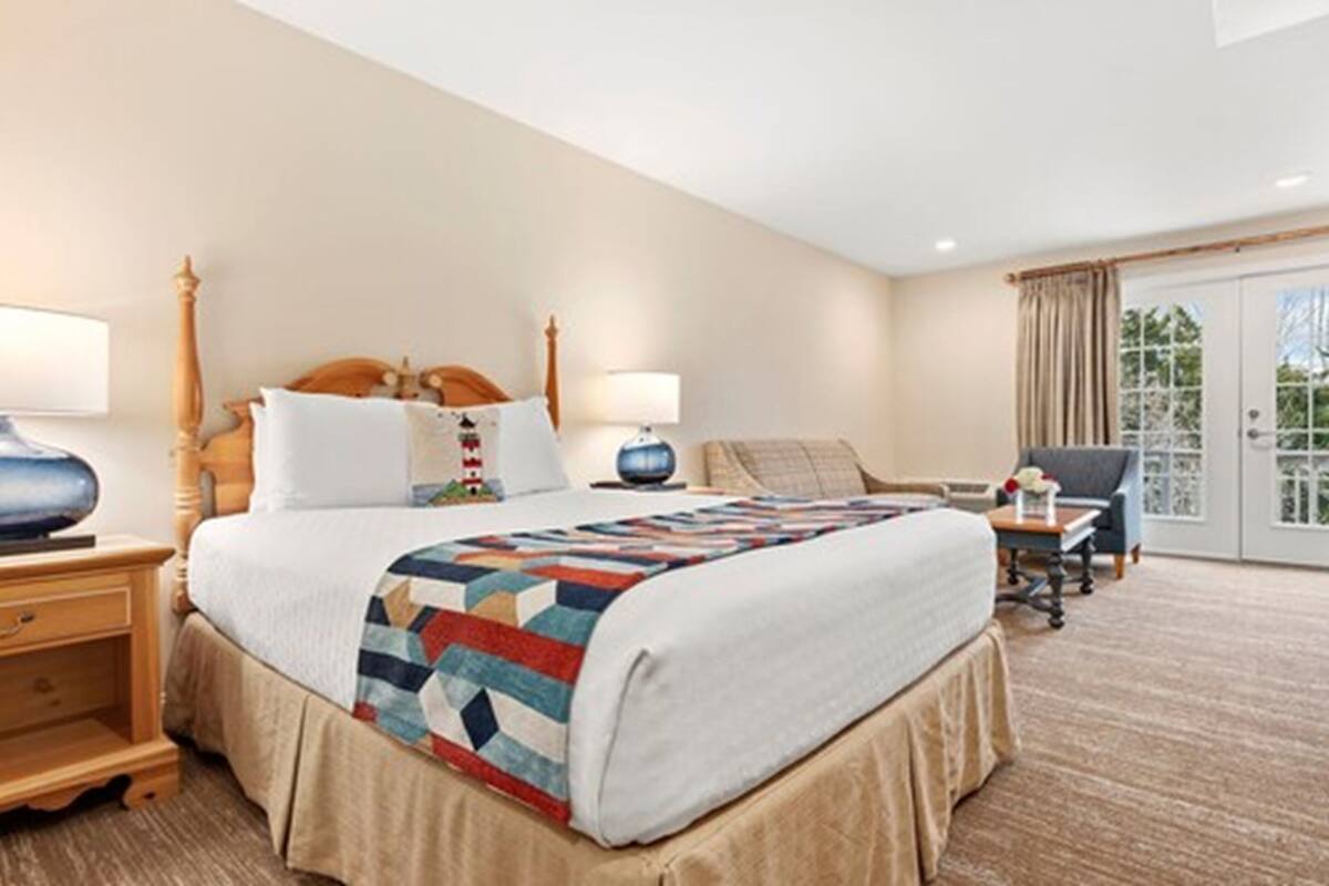 A hotel room with a large bed, two bedside tables, a chair, and a view of the outdoors.