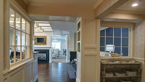A spacious hallway with a fireplace, a large window, and a built-in shelving unit. - Sag Harbor Inn (Sag Harbor)