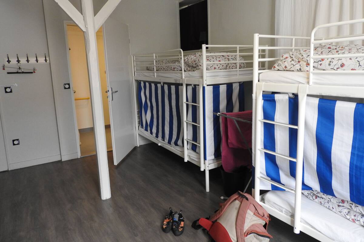Une chambre avec des lits superposés, une armoire et une porte donnant sur une autre pièce.