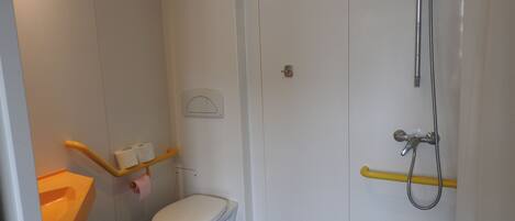 Un baño pequeño y funcional con inodoro, ducha y lavamanos.