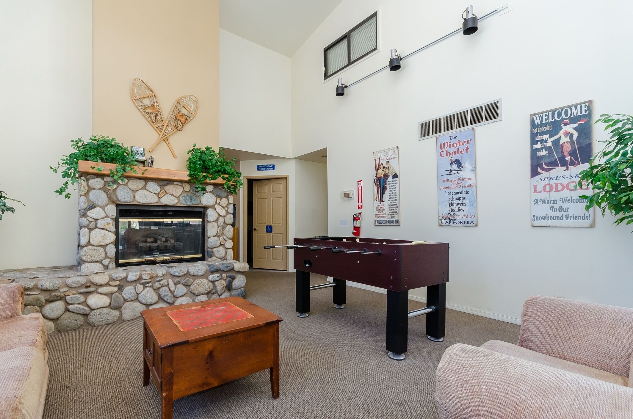 A cozy lobby with a stone fireplace, a foosball table, and comfortable seating.