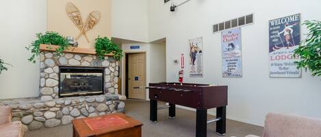 A cozy lobby with a stone fireplace, a foosball table, and comfortable seating.