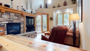 A cozy living room with a stone fireplace, a television, and a comfortable seating area.