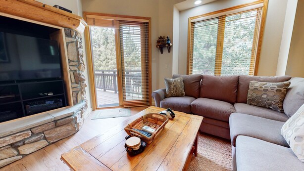A cozy living room with a stone fireplace, a comfortable sofa, and a wooden coffee table.