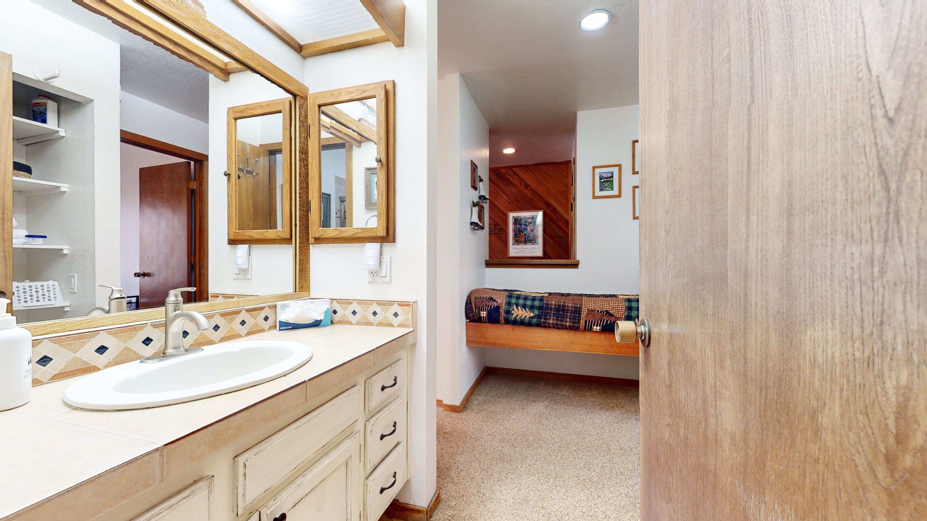 Un bagno con uno specchio grande, un lavandino e una panca in legno.