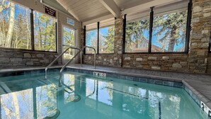 An indoor swimming pool with clear water, stone walls, and large windows. - Snowcreek #638 3 Bedroom Condo (Mammoth Lakes)