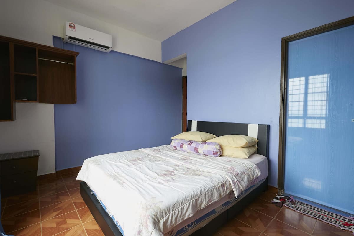 A bedroom with a bed, a wardrobe, and an air conditioning unit.