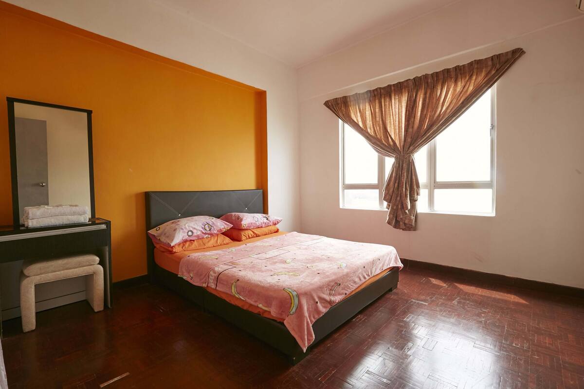 A bedroom with a bed, a nightstand, a mirror, and a window with curtains.